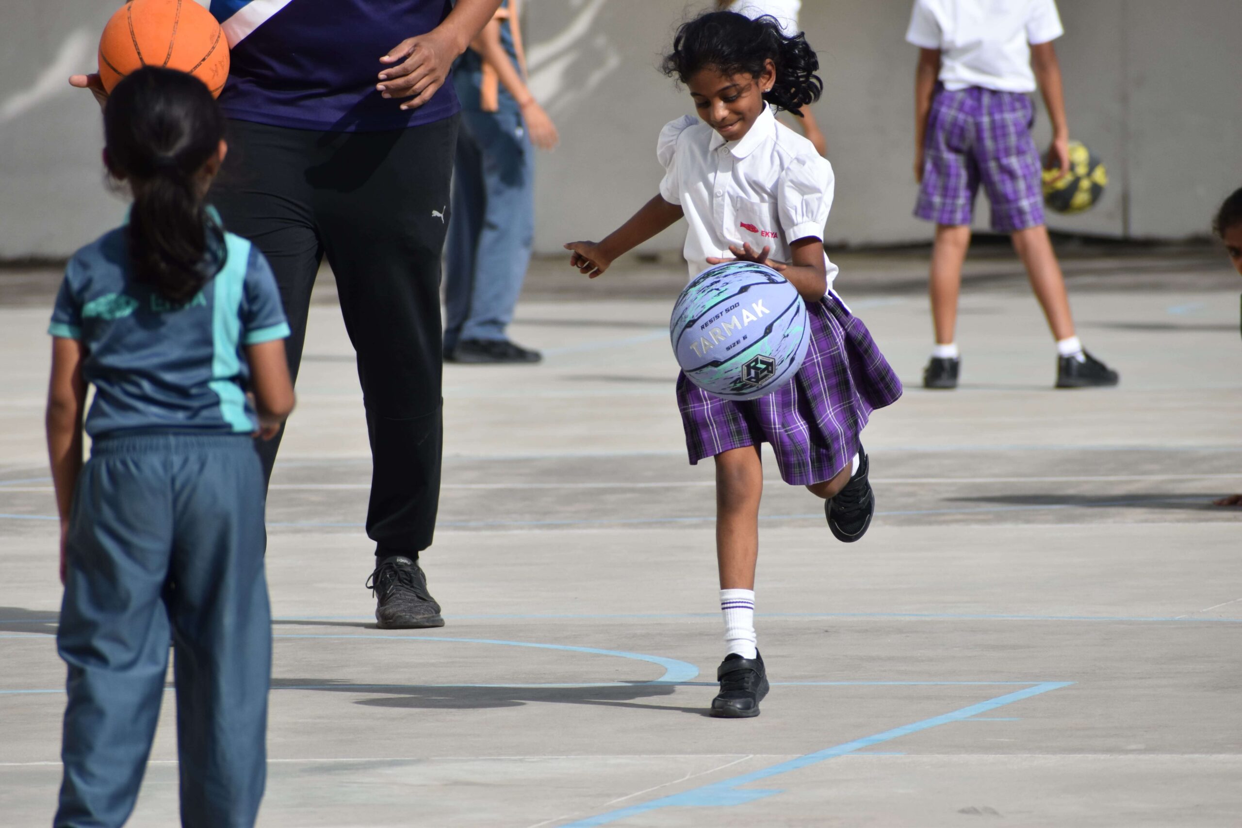 A young girl playing basketball on an outdoor court, enjoying school sports activities